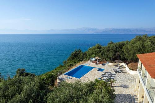 a house with a swimming pool next to the ocean at Beachfront Villa Seasun by PosarelliVillas in Agios Spyridon Corfu