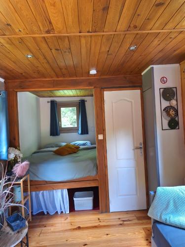 a bedroom with a bed and a wooden ceiling at Roulotte de Lustin in Profondeville