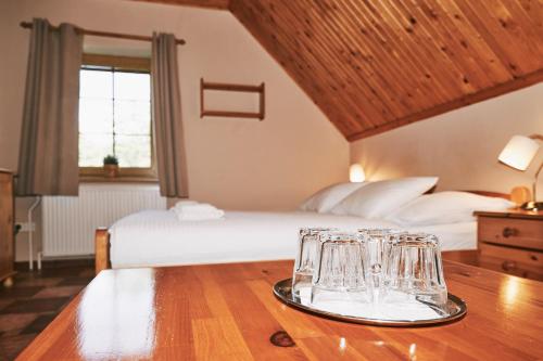a hotel room with a bed and glasses on a table at Penzion pod Šerákem in Ostružná