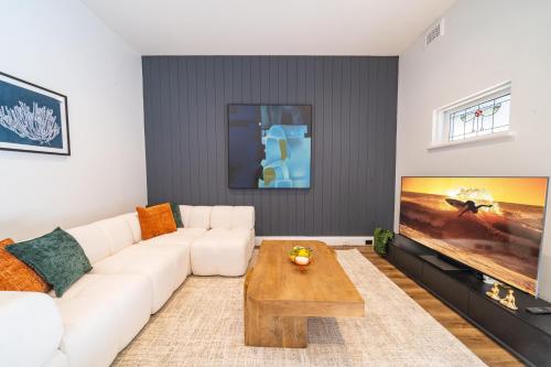 a living room with a white couch and a flat screen tv at Coastal Zen Oasis - Saltwater Pool & Heated Spa in Sydney