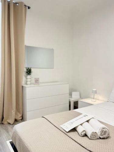 a white bedroom with two towels on a bed at La Torretta Apartment in Savona