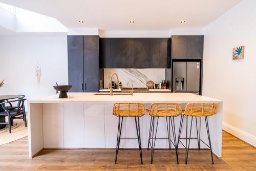 a kitchen with a white island with bar stools at Coastal Zen Oasis - Saltwater Pool & Heated Spa in Sydney