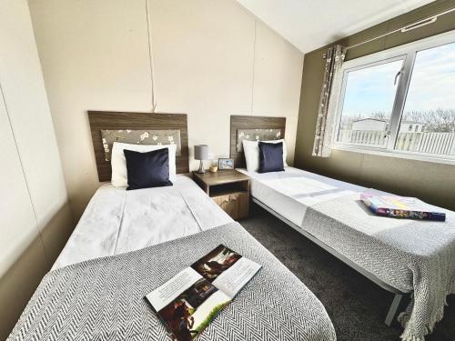 a bedroom with two beds and a window at Seaside Escape - Parkdean Resort Camber Sands in Camber