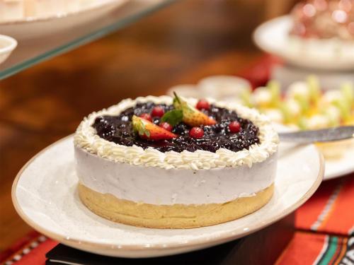 a cake with fruit on a plate on a table at Radisson Hotel Muscat Panorama in Muscat