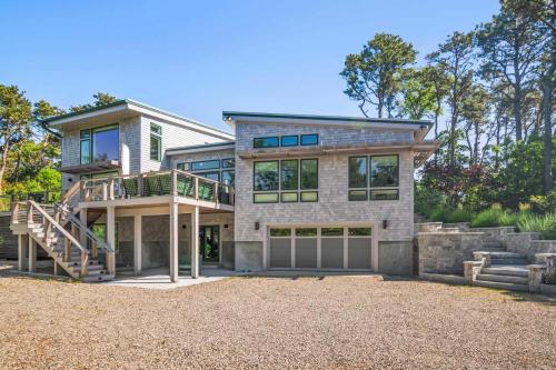 a large house with a staircase and a balcony at Modern Wellfleet Retreat with Stunning Outdoor Spaces in Wellfleet