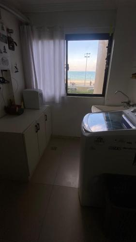 a kitchen with a window with a view of the ocean at Apartamento Frente Mar Centro in Itapema