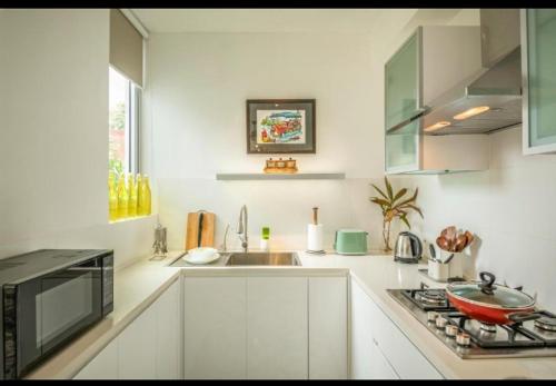 a white kitchen with a stove and a sink at 2bhk Villa with Private Pool, Anjuna Beach Goa in Assagao
