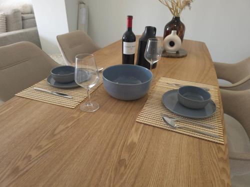 a wooden table with plates and glasses and wine bottles at New appartment with seaview in Almerimar