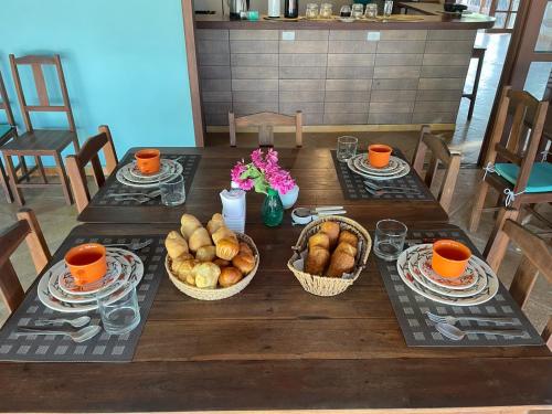 ein Tisch mit Körben voller Brot und Orangen darauf in der Unterkunft Pousada Vila Icaraí in Icaraí