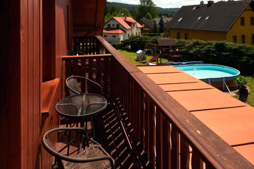 a balcony with a table and chairs and a swimming pool at Penzion pod Šerákem in Ostružná