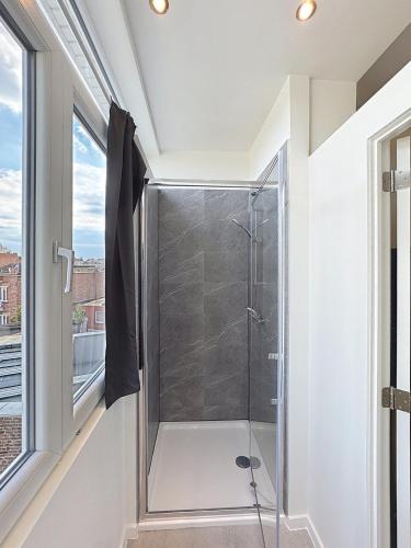 a glass shower in a bathroom with a window at Spacieux appartement une chambre in Brussels