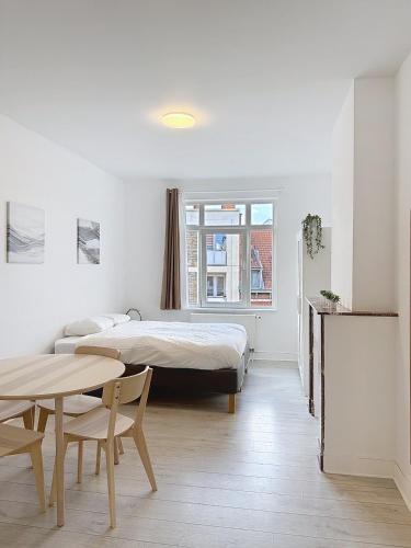 a white room with a bed and a table and a table sidx sidx at Spacieux appartement une chambre in Brussels