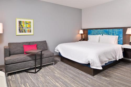 a hotel room with a bed and a chair at Hampton Inn & Suites By Hilton Long Island Farmingdale in Farmingdale