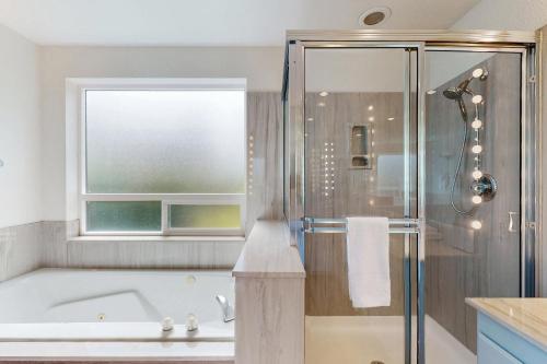 a bathroom with a tub and a shower with a window at Belfair Bliss in Belfair