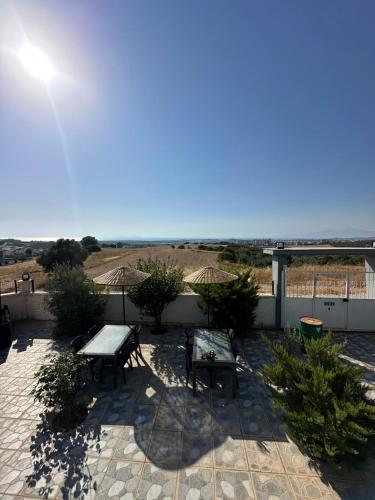 a patio with a table and benches and the ocean at Mavi Restaurant & Apartments 3 in Didim