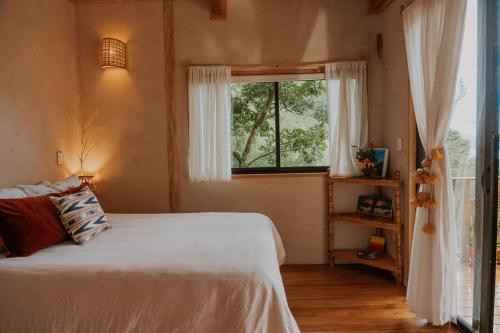 a bedroom with a white bed and a window at Casa Awänímä - Luxury Permaculture Hotel & Eco-Retreat in Tzununá