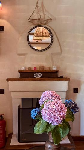 a fireplace with a vase of flowers and a mirror at Δυό Πηγές in Mouresi