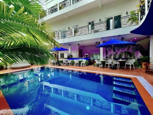 a swimming pool with chairs and umbrellas in a building at Pride Villa Cambodia in Phnom Penh