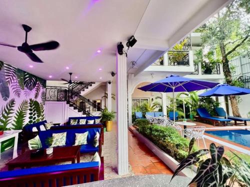 a patio with a pool and blue chairs and umbrellas at Pride Villa Cambodia in Phnom Penh