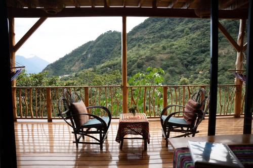 a porch with chairs and a table with a view of a mountain at Casa Awänímä - Luxury Permaculture Hotel & Eco-Retreat in Tzununá