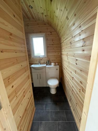 a bathroom with a toilet and a sink in a wooden wall at Sutton Fields Pod 