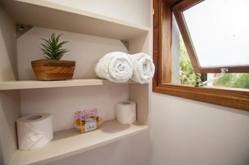 une salle de bains avec une étagère, des serviettes et une fenêtre. dans l'établissement Madre e Hija (refugio de montaña), à El Chalten