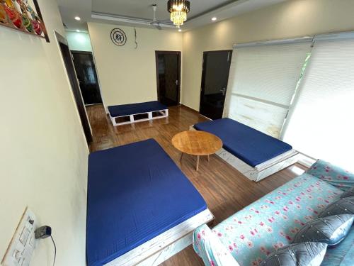 a room with two beds and a table and a couch at GoBravo 71- 2BHK Farm with Pool & Garden Sector 150 Noida in Greater Noida