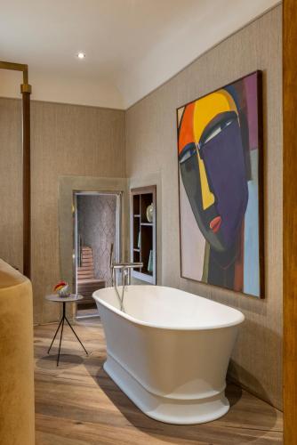 a bath tub in a bathroom with a painting on the wall at The James Suite Hotel Firenze 1564 - Small Luxury Hotels of the World in Florence