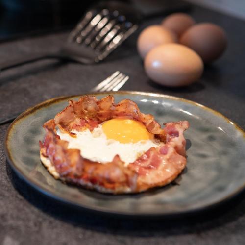 a fried egg on a plate with bacon at L' Appart de Grand-Mère in Oudenburg