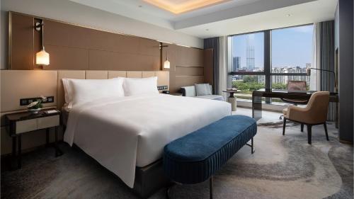 una camera da letto con un grande letto bianco e una scrivania di InterContinental Hotels Zhengzhou Zhengdong a Zhengzhou