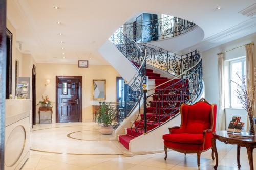 a spiral staircase in a living room with a red chair at Rheinhotel Schulz in Unkel