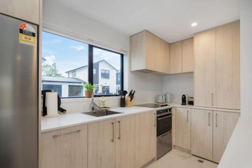 a kitchen with wooden cabinets and a large window at Trentham Stylish 2-BR Retreat in Upper Hutt