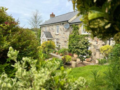 a stone house with a garden in front of it at Rose Cottage in Saint Hilary