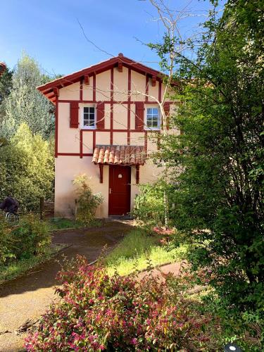 une petite maison avec une porte rouge dans une cour dans l'établissement cottage « maison du golf » à Moliets, à Moliets-et-Maa