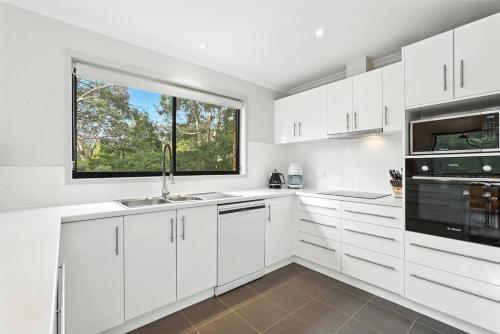 a white kitchen with white cabinets and a window at Tranquil Bush Outlook Near City in Lindisfarne