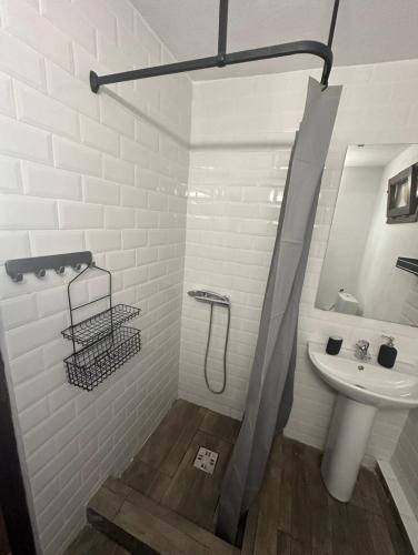 a white bathroom with a sink and a shower at Casuța din Domnești in Domneşti