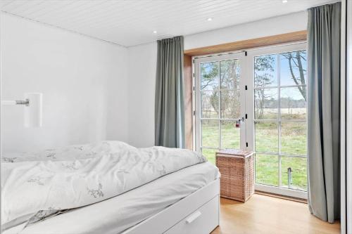 a white bedroom with a bed and a large window at 2315-Stege-Kongens-Enge-15 in Stege