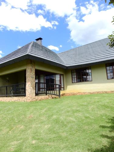 a yellow house with a black roof and a yard at Fairways Holiday Accommodation in Drakensberg Garden
