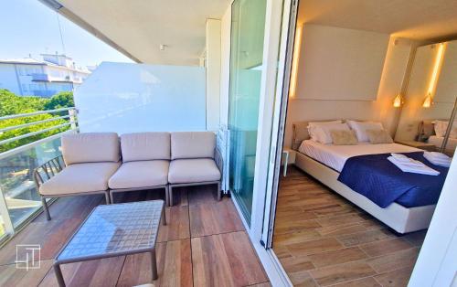 a balcony with a bed and two chairs in a room at HT - Luxury apartment at Palm Beach Jesolo in Lido di Jesolo