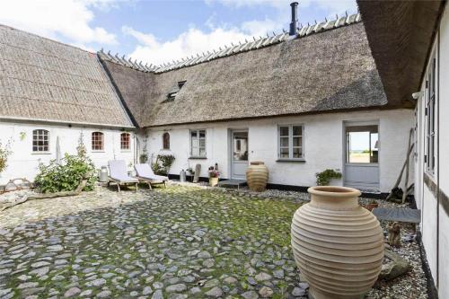 a white house with a large vase in the yard at 6005-Stege-Hjelmvej-15 in Stege
