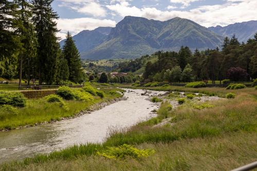 a river in a field with mountains in the background at Hotel Posta in Comano Terme