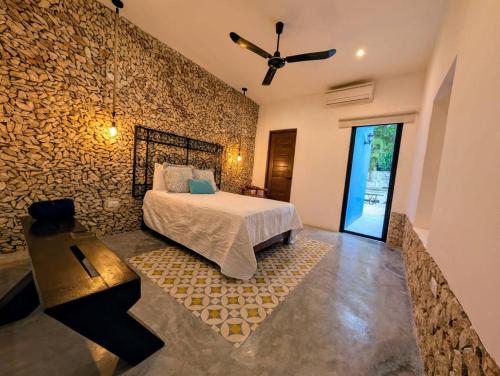 a bedroom with a bed and a stone wall at Casa Kiiwik - Luxury Property with a Private Outdoor Pool and Parking in Central Merida in Mérida