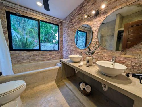 a bathroom with two sinks and a tub and a toilet at Casa Kiiwik - Luxury Property with a Private Outdoor Pool and Parking in Central Merida in Mérida