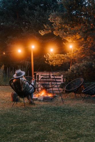 a man sitting in a chair next to a fire at Przystanek Roztocze in Susiec