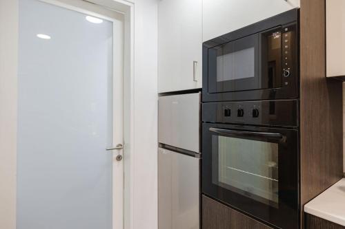 a kitchen with a black microwave and a refrigerator at Central Apartment in St Julians in St Julian's