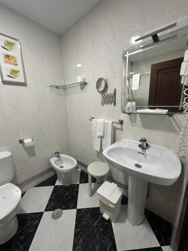 a white bathroom with a sink and a toilet at Hotel Mediante in Ribadeo