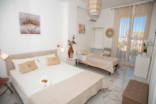 a white bedroom with two beds and a window at Azzurro Mare in Isola delle Femmine