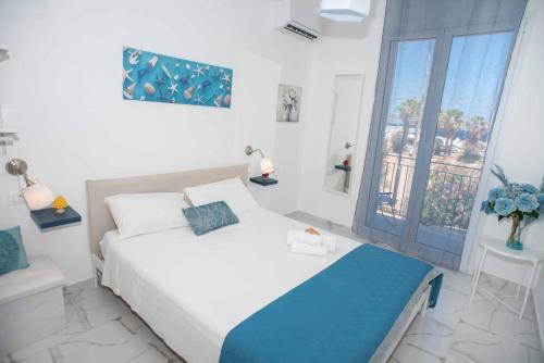 a white bedroom with a bed and a window at Azzurro Mare in Isola delle Femmine