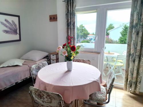 a room with a table with a vase of flowers on it at Apartments Panonija in Novalja