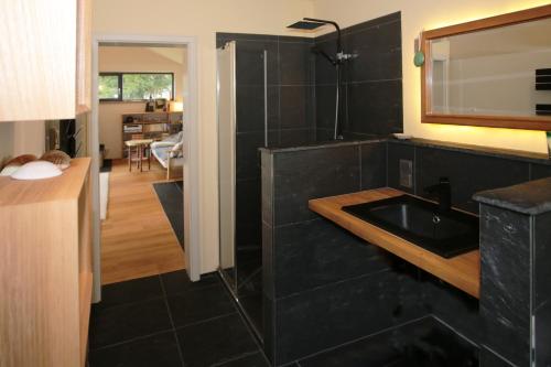 a black bathroom with a sink and a mirror at Holzhaus mit Kamin - Am Forellenfluss in Heinersdorf